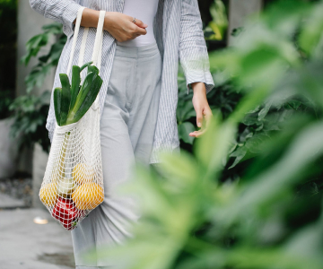 The girl is walking with groceries in her hands