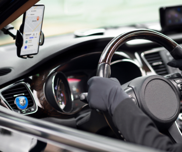 Someone is sitting behind the wheel and a mobile phone with 
                  a Google map near the steering wheel